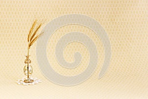 glass vase with a few ripe spikelets of rye Secale cereale on a white round knitted napkin on a beige background.