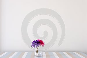 Glass vase of flowers on the table over white wall