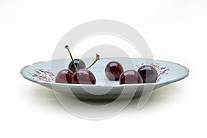 Glass vase with fresh wet cherries isolated on white background