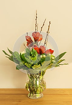 Glass vase with red Amaryllis and green leaves