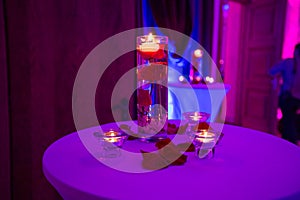 Glass vase with red roses water and light candles