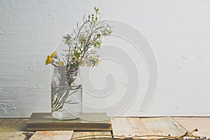 Glass vase with some flowers in a bouquet on a wooden shelf. Spring interior decoration against a white background.