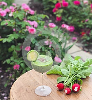 Glass of vegetable juice on the table. A bunch of radishes