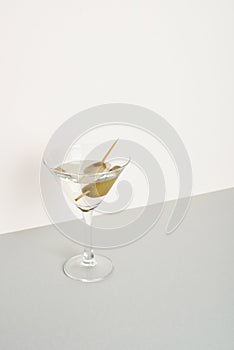 Glass of vermouth with olives on grey surface