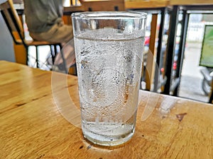 Glass of very cold water and water drops on table.
