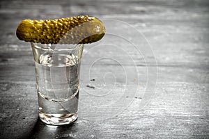 Glass of vodka with pickled gherkins.