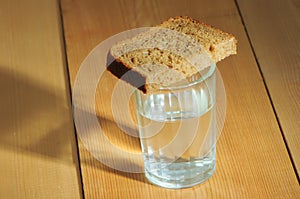 Glass of vodka and a piece of bread on a wooden table