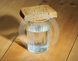 Glass of vodka and a slice of bread on a wooden table