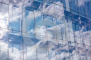 Glass wall of modern office building with cloudy sky reflection