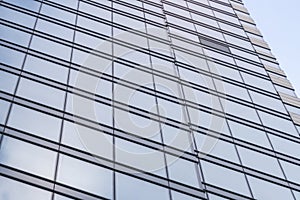 Glass walls of modern building with soft cloud reflection. Light blue business background