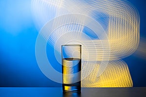 Glass of water on an abstract background. Blue yellow beautiful background