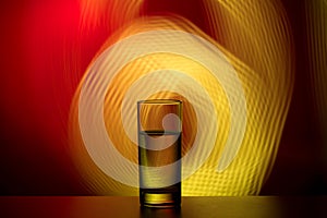 Glass of water on an abstract background. Red yellow beautiful background