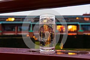 Glass of water on the balcony with evening lights background