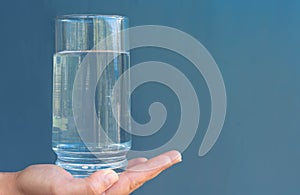 Glass of water with a blue copy space background. Hydration