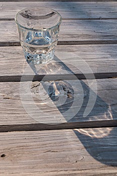 Glass of water casting shadow on wooden table