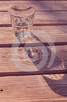 Glass of water casting shadow on wooden table - split toning