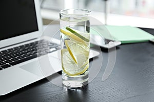 Glass of water with citrus fruits on dark table