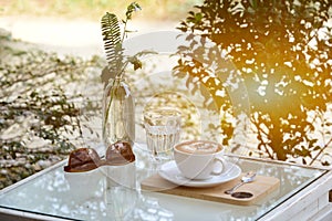 Glass of water and coffee and sunglasses on table with outdoor photo