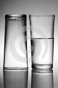 A glass of water beside an empty glass. Conceptual image