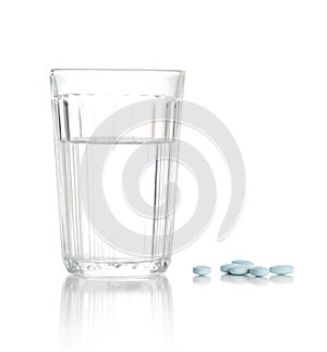 Glass with water and a heap of tablets, pills