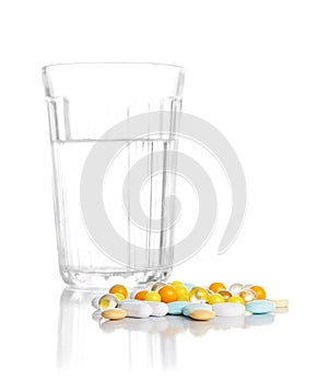 Glass with water and a heap of tablets, pills