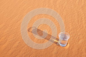 Glass of water on a hot desert land