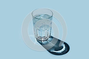 Glass of water with ice on blue background