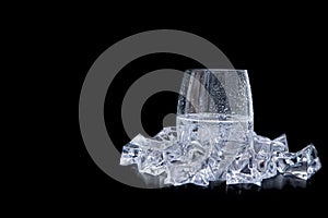 Glass of water with ice and bubbles on black background