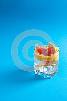 A glass of water with ice cube and a slice of fresh grapefruit