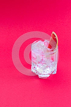 A glass of water with ice cube and a slice of fresh grapefruit