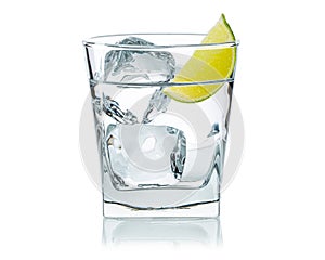 Glass of water with ice cubes and fresh lime slice. Cold lemonade. Frozen water in shape of cube.