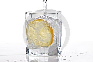 Glass of water, ice and slice of lemon with splash