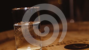 Glass of water with ice on a wooden barrel