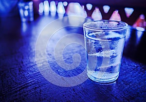 A glass of water with ice, on the wooden table.