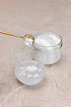 Glass of water and a jar of collagen goodnesson a marble beige background