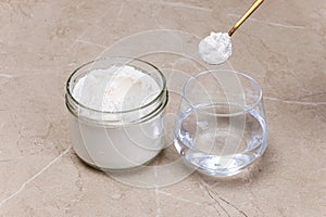 Glass of water and a jar of collagen goodnesson a marble beige background