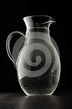 Glass water jug on the black background