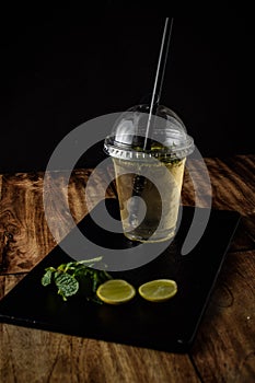 glass of water with lemon and ice on wooden background, green tea with lemon and mint,