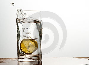 Glass of water with lemon with splash with copy space