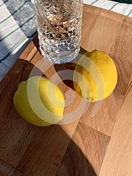 a glass of water with lemons on a wooden board