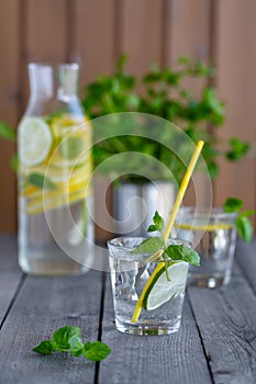 Glass of water with lime and mint on a old wooden table