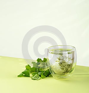 Glass of water with liquid chlorophyll and fresh herbs on a green table. Concept of superfood, healthy eating, detox and diet.
