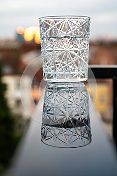 Glass of water with luxury crystal design reflecting on a wet black surface, Belgium