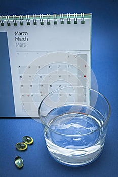 Glass of water and pills isolated on blue