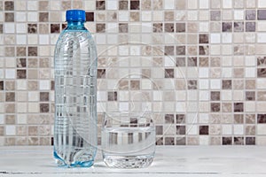 Glass of water and plastic water bottle on kitchen table