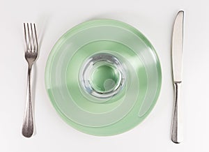 Glass of water in a plate with knife and fork isolated on white