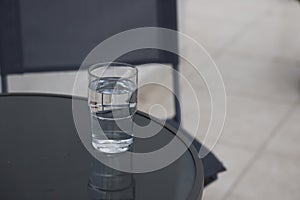 Glass of water on a table in a cafe, minimalism, background in gray tones