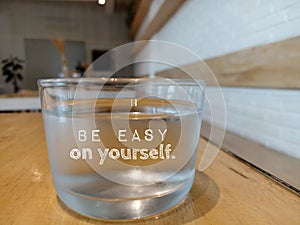 Glass of water with text - Be easy on yourself. Self love and care concept. Healthy lifestyle with glass of mineral water/