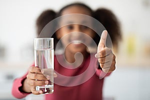 Glass of water and thumb up, unrecognizable girl drinking water