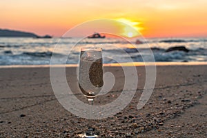 A glass of water was put with sand on the beach